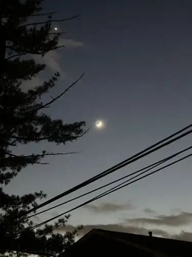 Crescent moon's glow in the deepening night.